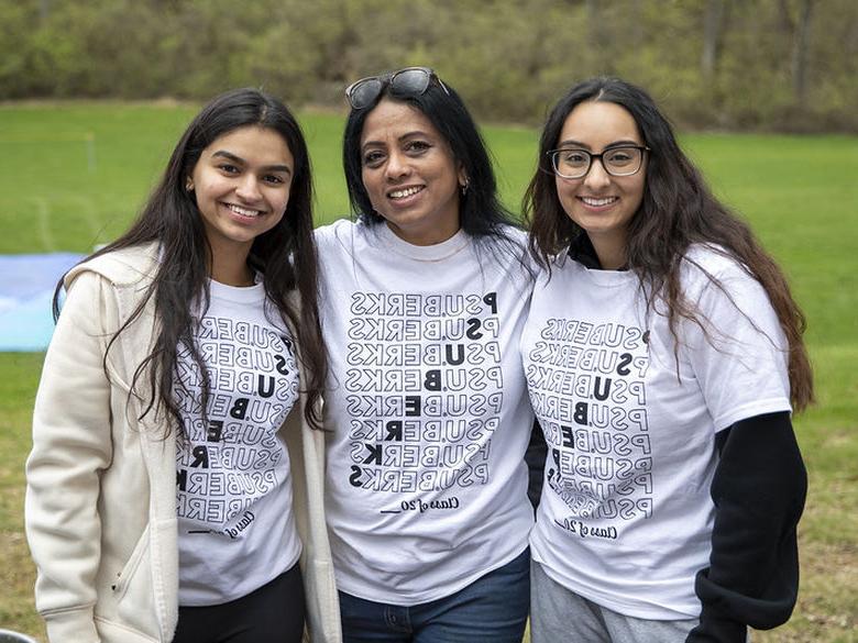 Two students pose for a photo with a professor.