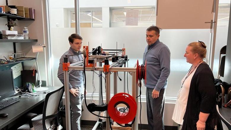 Three people view technological prototype