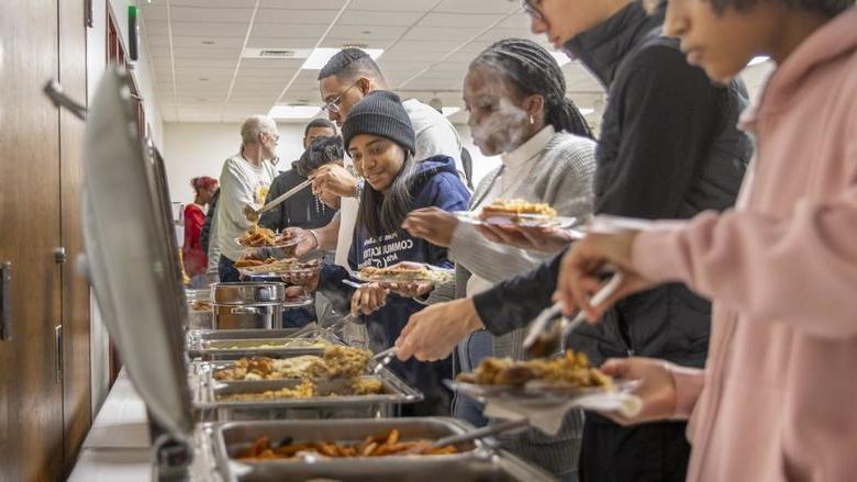 Students serve themselves food from chafing dishes.